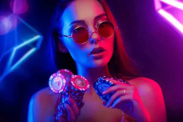 4777BTE ক্যাসিনো — প্রবেশ করুন আমাদের বিলাসবহুল ক্যাসিনো অভিজ্ঞতায় নিয়ন আলোয় আলোকিত পরিবেশে ক্যাসিনো চিপ হাতে এক অভিজাত নারী—যা 4777BTE–এর প্রিমিয়াম অনলাইন ক্যাসিনো পরিবেশকে তুলে ধরে।